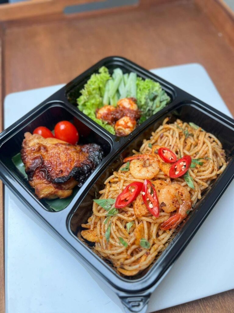 Bento set with spicy prawn spaghetti, grilled chicken and salad with sambal quail eggs, prepared by Catering Corner