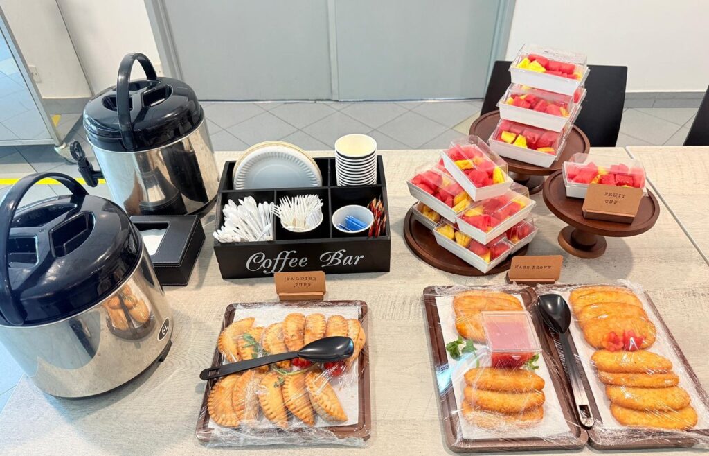 Tea break spread for a staff event with a coffee bar, fruit cups, sardine puffs and hash browns