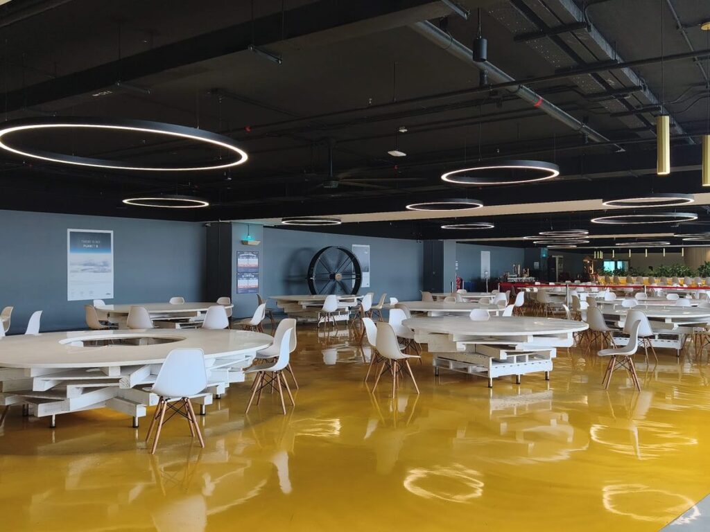 Large staff cafeteria dining hall with round tables, ring lighting and a yellow floor, run by Catering Corner in Singapore