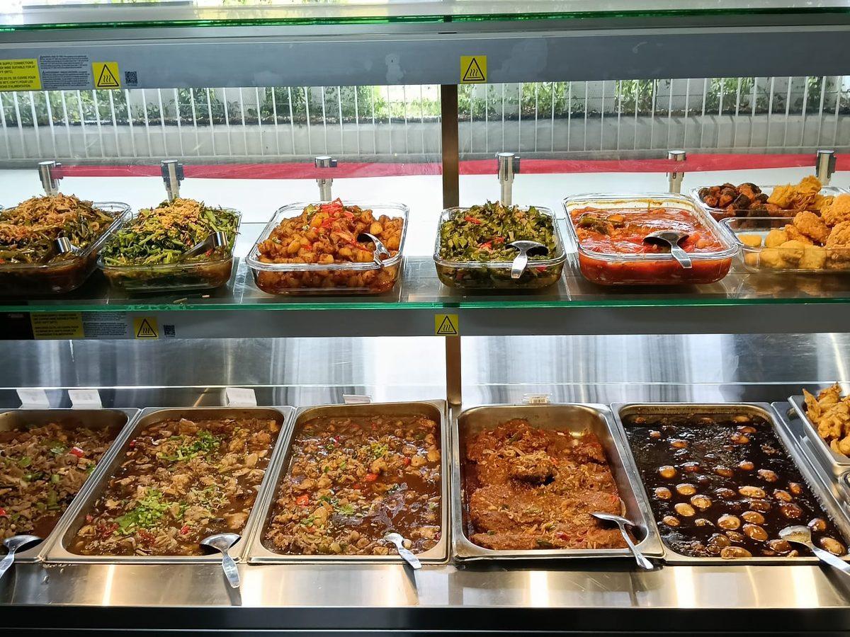 Economic rice counter at a Catering Corner staff canteen in Singapore, with vegetables, braised meats, braised eggs and fried fish under a heated display