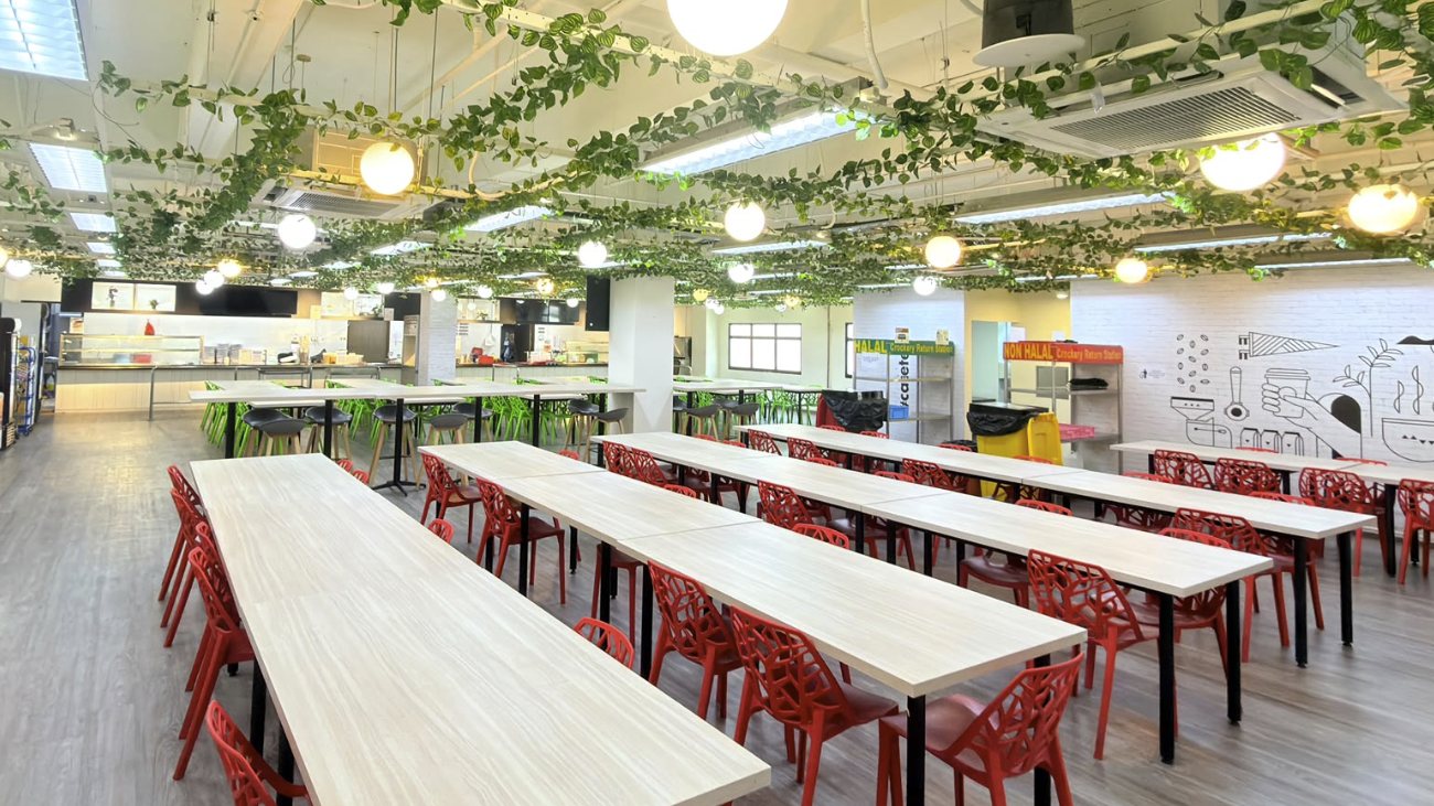 Staff canteen dining hall with long tables, red chairs and separate halal and non-halal crockery return stations, run by Catering Corner in Singapore