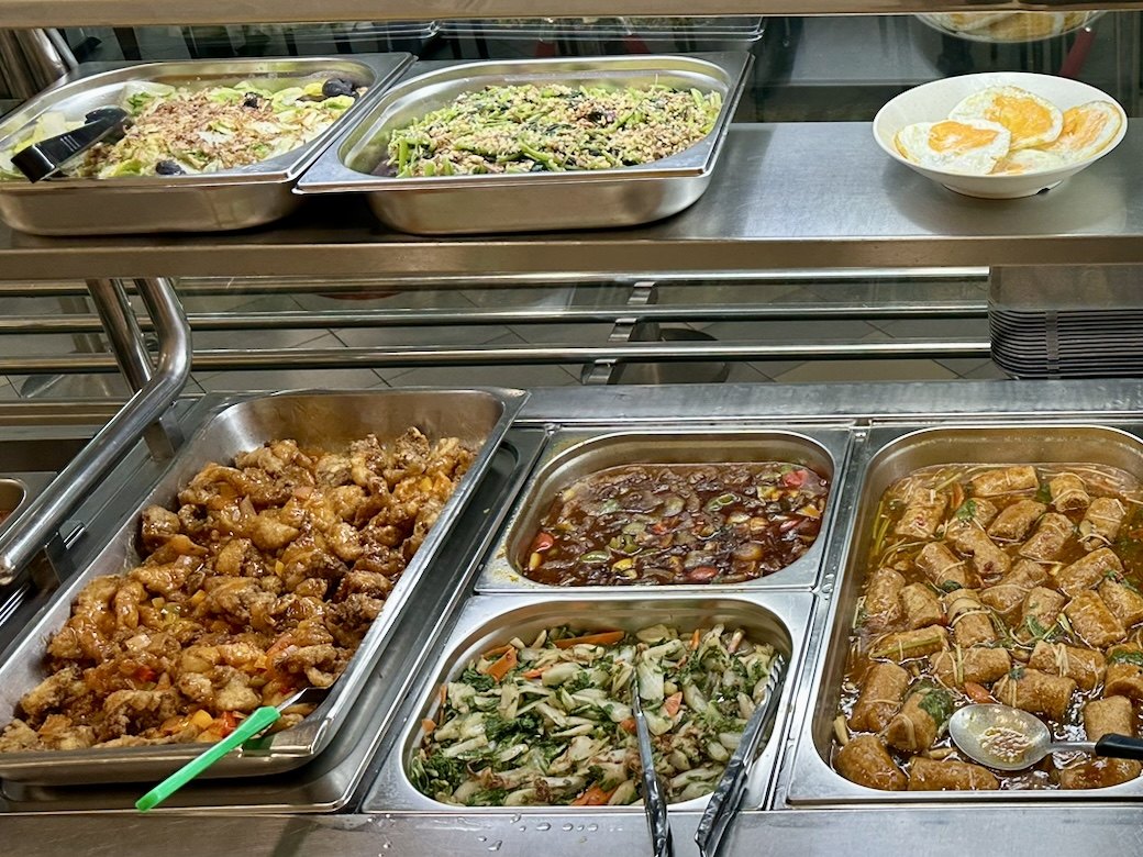 Economic rice line at a Catering Corner staff canteen in Singapore, with fried chicken, vegetables, tofu rolls and fried eggs