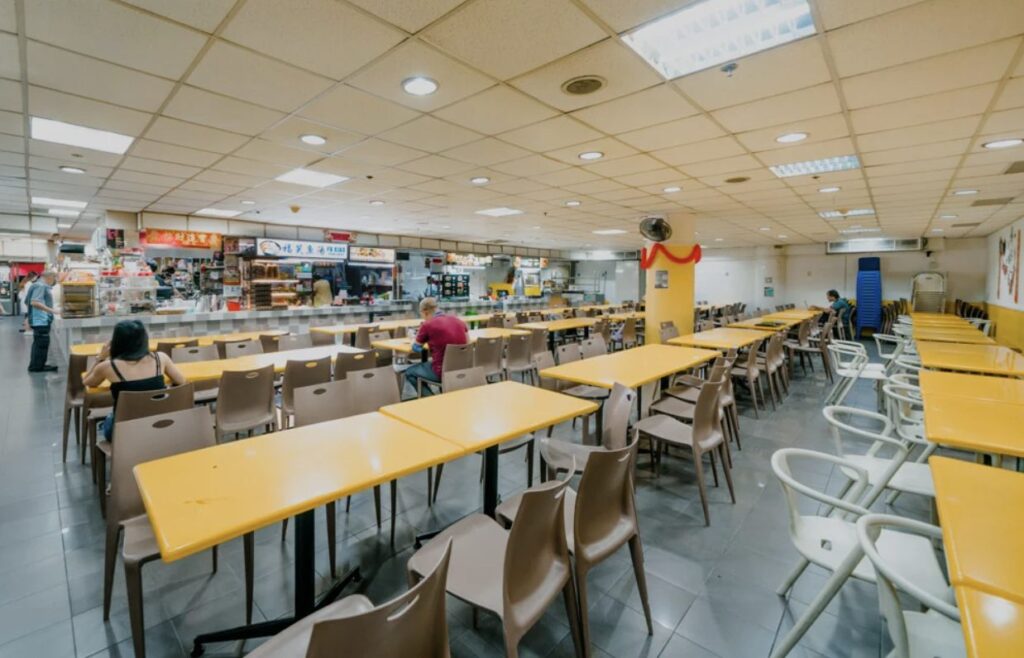 Large staff canteen dining hall with food stalls and long tables in Singapore
