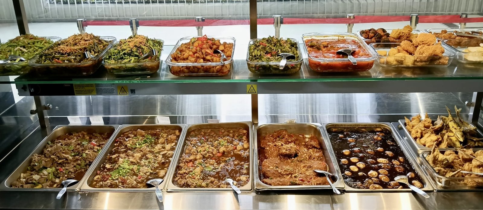 Hot food servery at a Catering Corner staff canteen in Singapore, with vegetables, curries, braised eggs, fried chicken and fried fish