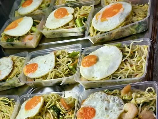 Packed fried noodles with prawns, vegetables and a fried egg, prepared as supper for night-shift staff at a Catering Corner staff canteen