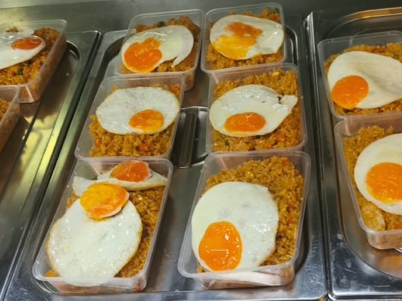 Packed fried rice topped with fried eggs, prepared as supper for night-shift staff at a Catering Corner staff canteen
